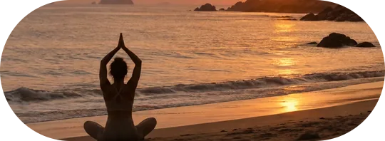 Pessoa a meditar numa praia ao pôr do sol
